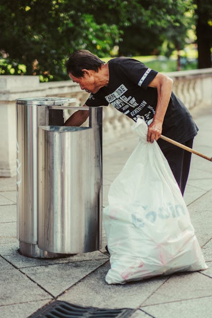 A large pile of black rubbish bags filled with waste is stacked against a modern tiled wall exterior. Some of the bags are partially opened, revealing plastic bottles and other debris inside. The bags